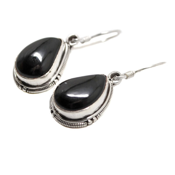 A pair of sterling silver dangle earrings set with teardrop onyx cabochons against a white background
