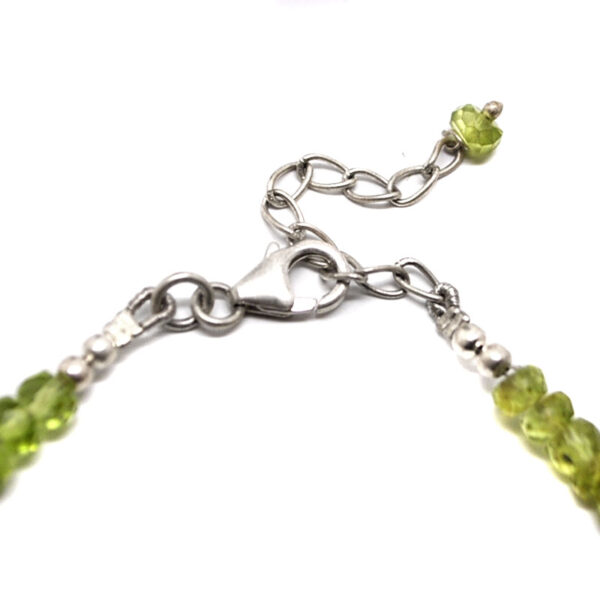 A beaded necklace featuring faceted peridot with a sterling silver lobster claw clasp against a white background