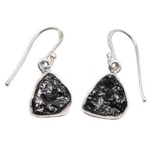 A pair of sterling silver dangle earrings set with rough black tourmaline against a white background