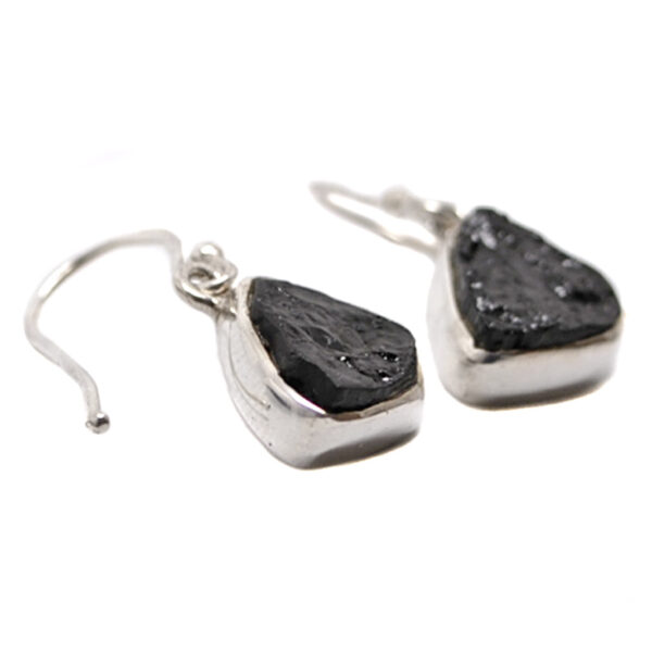 A pair of sterling silver dangle earrings set with rough black tourmaline against a white background