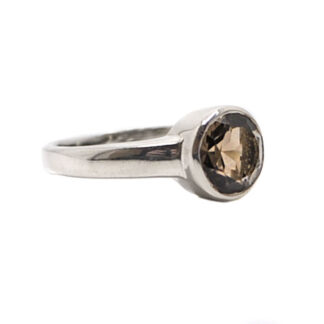 A simple sterling silver ring featuring a round faceted smokey quartz gemstone against a white background