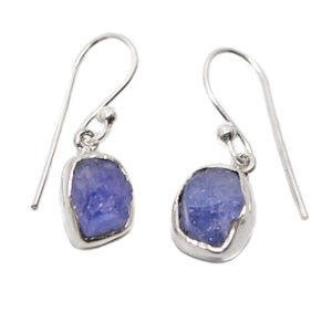 A pair of sterling silver dangle earrings set with rough tanzanite gemstones against a white background