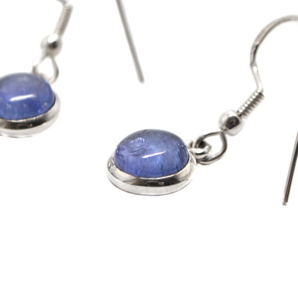 A pair of sterling silver dangle earrings set with round tanzanite gemstones against a white background