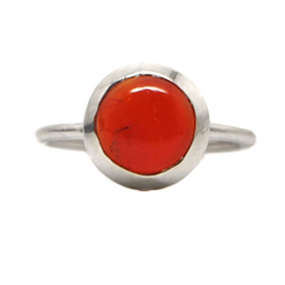 A sterling silver ring set with a round carnelian cabochon against a white background