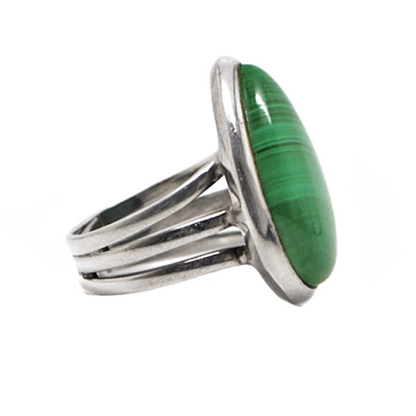 A sterling silver ring with a split band set with a teardrop green malachite cabochon against a white background