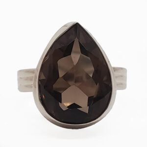 An teardrop faceted smoky quartz set into a simple sterling silver ring against a white background