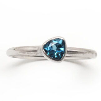 Blue Topaz Triangular Faceted Sterling Silver Ring with a thin band against a white backround.