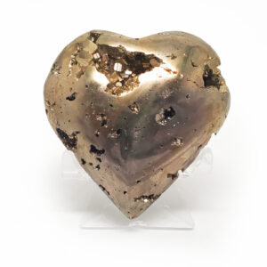 A carved pyrite heart carving with exposed crystals on a clear stand against a white background