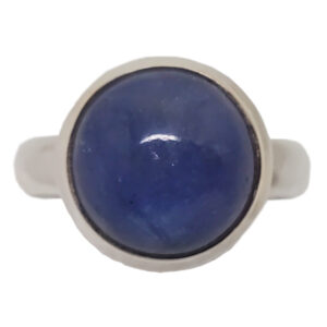 A round tazanite cabochon set into a simple sterling silver ring from the side against a white background