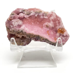 Pink smithsonite on a clear display stand against a white backround.