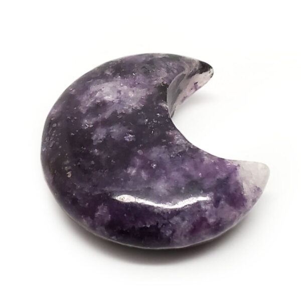 A carved lepidolite moon cresent against a white background